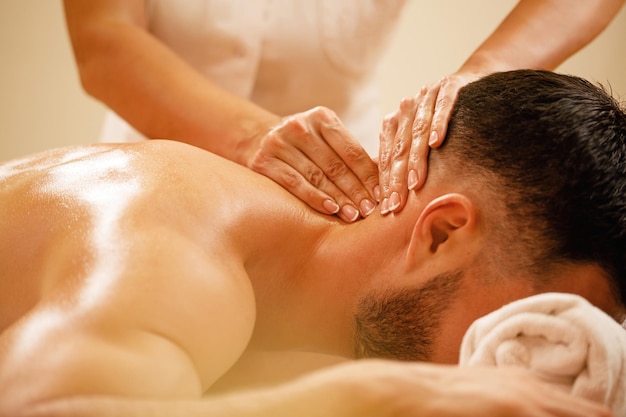 Closeup of therapist massaging man's neck during spa treatment