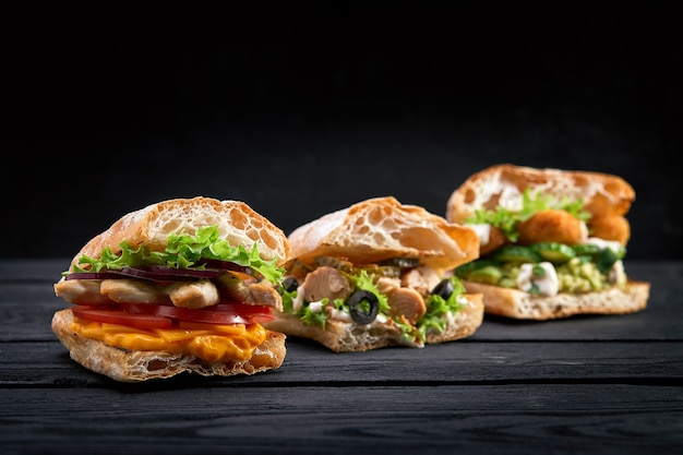 Closeup of three different Appetizing sandwiches burgers on black wooden background