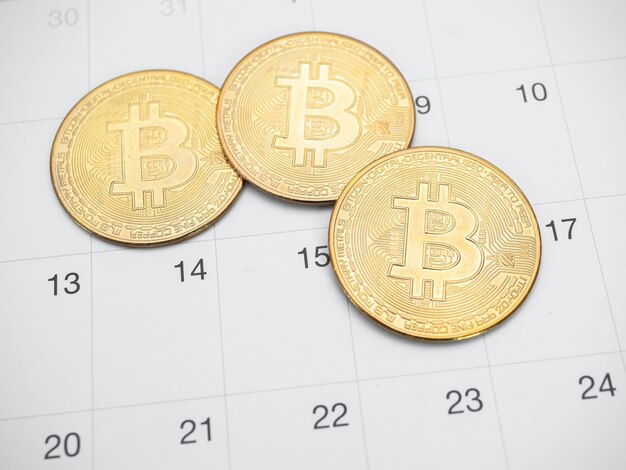 Closeup three gold bitcoin on calendar