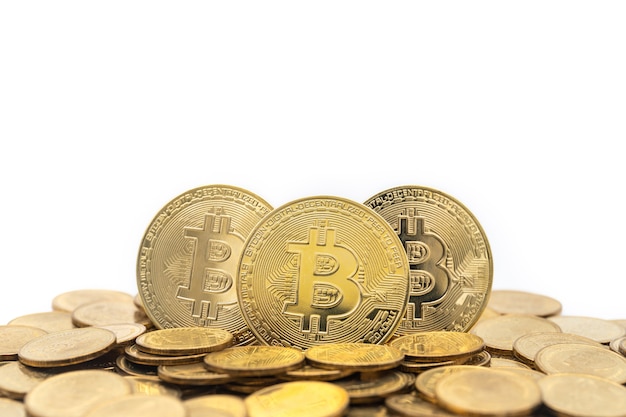 Closeup of three gold bitcoin coin with pile of coins