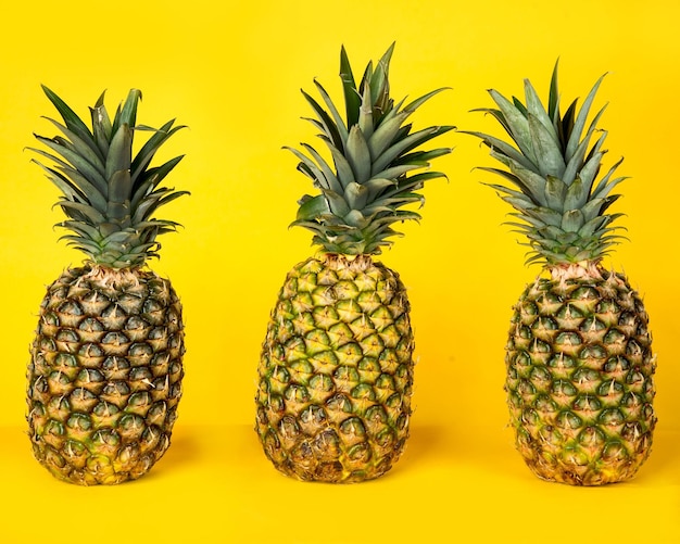 Closeup of three pineapples isolated on a yellow background