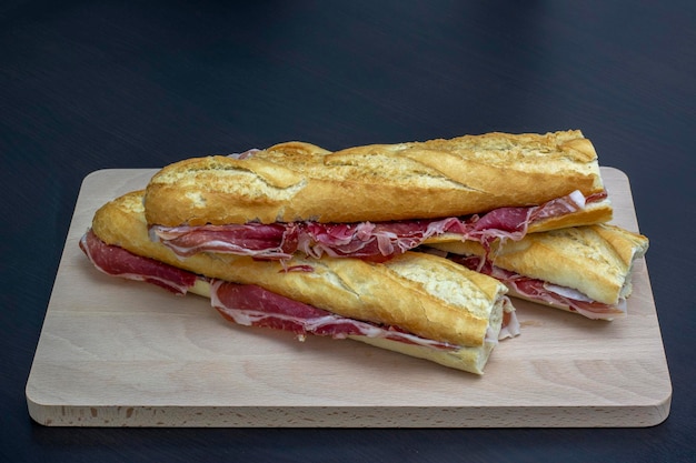 Closeup of three spanish iberic ham sandwich served in a wooden plate