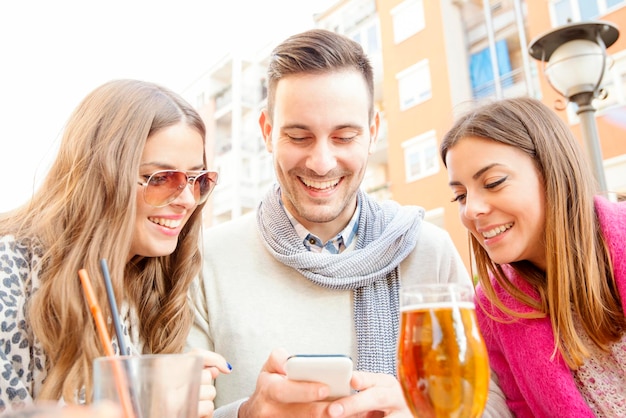 Closeup of three young cheerful people drinking beer outdoors