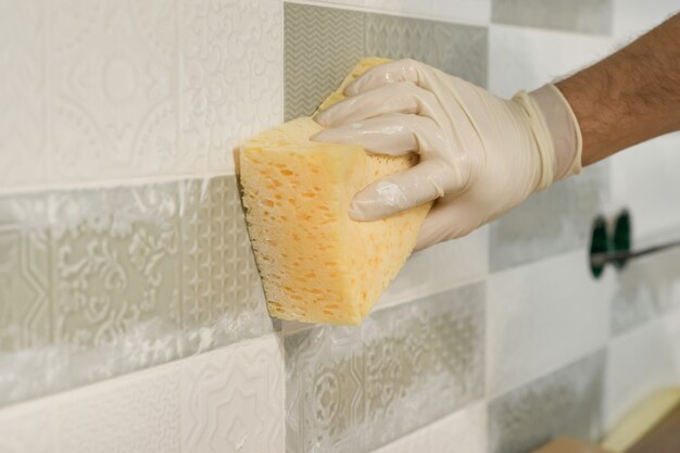 Photo closeup of tiler hand rubbing tile