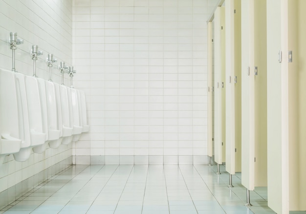 Closeup tiles wall in the toilet of man with toilet view by urinals and small room