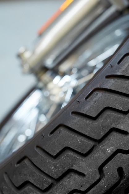 バイク タイヤのクローズ アップ傾斜ビュー カスタム モダン スポーツ バイク用に設計されたタイヤ クラシック バイクの前輪のサスペンション ビンテージ ショック アブソーバーとクローム ボディのリフレクターのメンテナンス