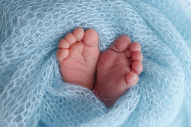 Closeup of tiny cute bare toes heels and feet of a newborn girl boy Baby foot on blue soft coverlet blanket Detail of a newborn baby legs Macro horizontal professional studio photo