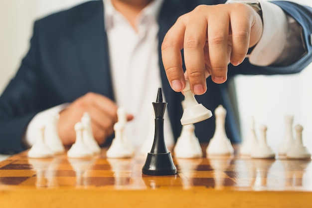 Photo closeup toned businessman making move with white pawn on chess board