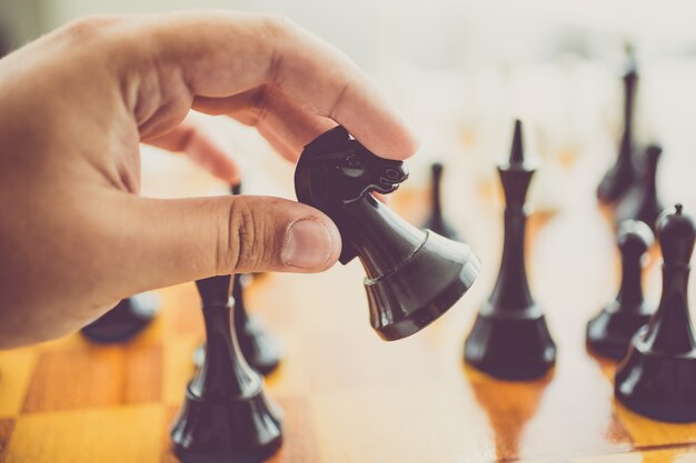 Фото Крупным планом тонированный человек делает ход с черной лошадью в шахматной игре