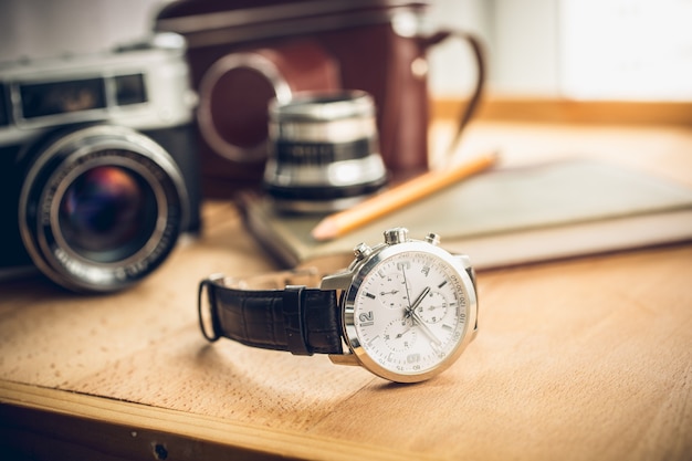 Photo closeup toned shot of male watches lying on table against photography retro set