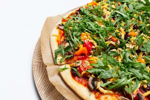 Photo closeup top view of homemade vegan pizza on wooden plate on white background