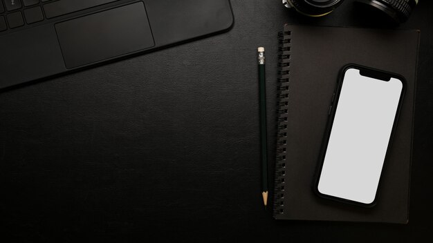 Closeup top view modern dark study table smartphone screen mockup on black surface