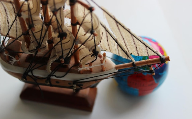 Photo closeup top view of wooden masted ship model and blurred globe behind bowsprit
