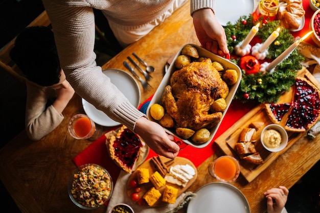 Closeup top view of young father male putting dish with baked hot turkey on holiday dinner table served for Christmas family party