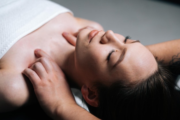 Крупным планом вид сверху молодой женщины, лежа на массажном столе во время массажа плеч и шеи