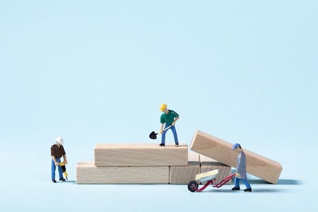 Closeup of toy construction workers doing their job on a blue wall