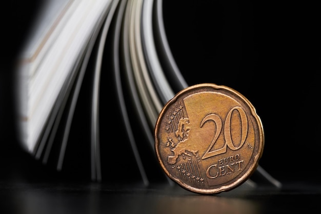 Closeup of a twenty cent euro coin on the background of magazine pages