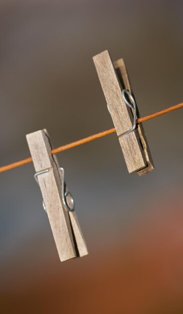 Closeup of two clothing pegs on a washing line outside against a blurred background Wooden clothespins used to clip and hang clean laundry in the sun to dry as part of household and domestic chores