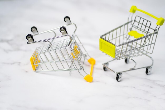 Primo piano di due metallo vuoto piccolo giocattolo in miniatura carrello della spesa su sfondo bianco. shopping, supermercato, concetto di vendita. raccolta di carrelli della spesa.