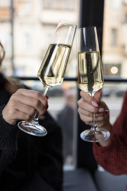 Photo closeup of two female hands toasting with champagne in restaurant