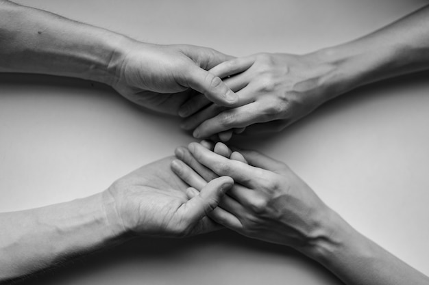 Closeup on two pairs of hands holding each other at a table