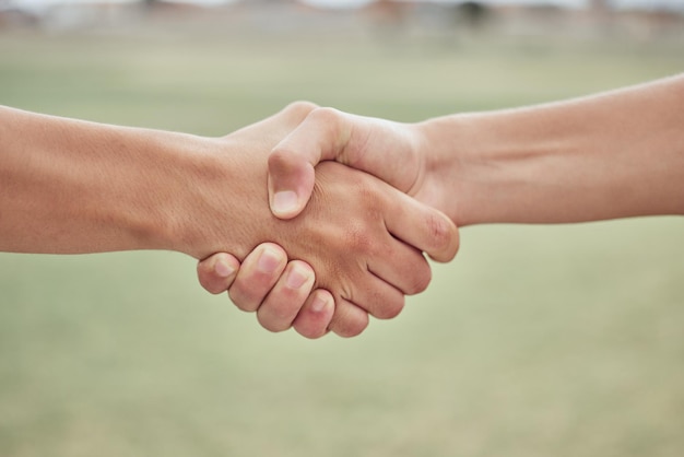 Closeup of two unknown baseball players shaking hands while standing on a grass field Two sportsmen greeting or congratulating on a good game