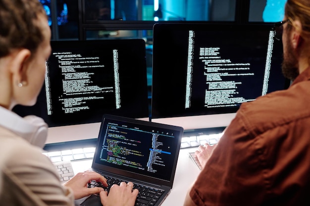 Closeup of two young developers working over data decoding software