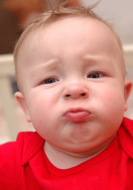 Photo closeup of unhappy caucasian boy in red t-shirt.