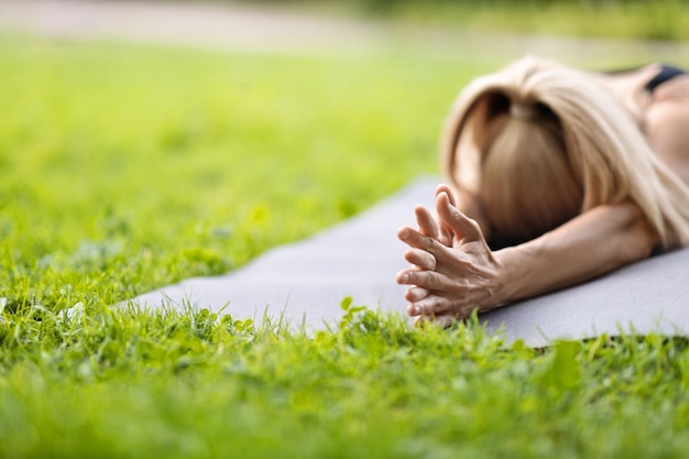 Closeup of unrecognizable blonde lady lying on yoga mat