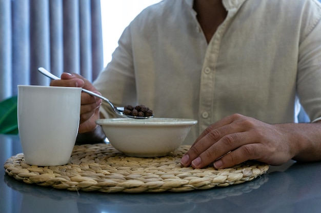 朝食に穀物を食べている認識できない男のクローズ アップ