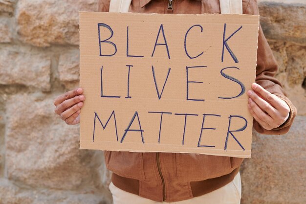 Photo closeup of unrecognizable man holding black lives matter cartoon banner while fighting for rights