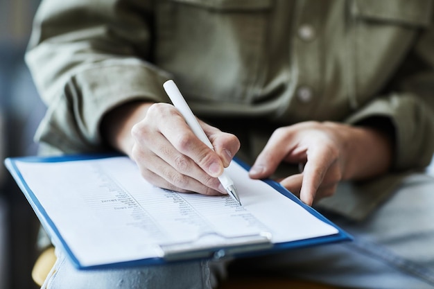 Closeup of unrecognizable person writing on clipboard with grammar notes in english copy space