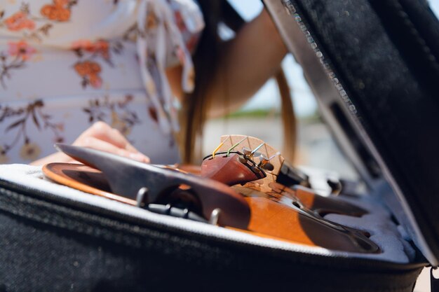 closeup of unrecognizable woman on street closing violin case putting it after playing