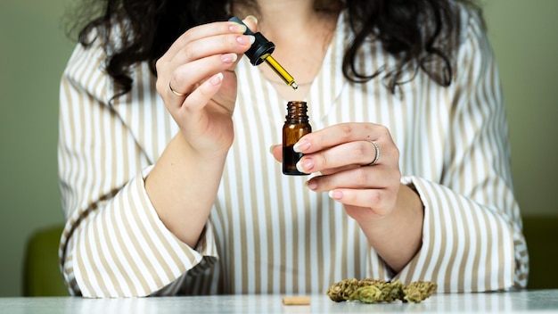 Photo closeup of unrecognizable woman using and holding medical cannabis oil concept of herbal and alternative medicine