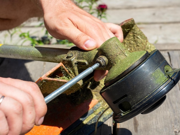 Closeup of unscrewing the screw on the gearbox of the grass mowing trimmer Maintenance of equipment