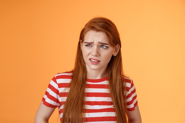 Closeup unsure redhead teenager frowning uncertain having doubts look perplexed left side copy space...