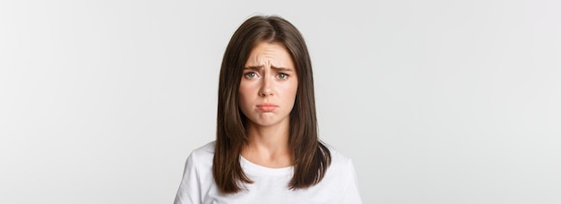 Photo closeup of upset and gloomy cute brunette girl sulking looking miserable