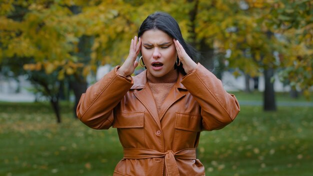 Closeup upset hispanic girl standing outdoors suffer from feeling unwell headache malaise soreness