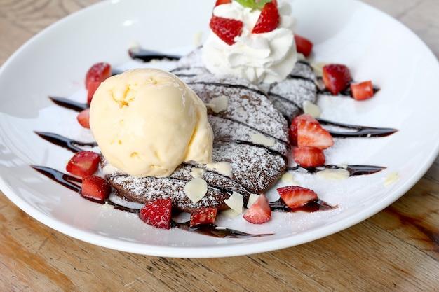 Closeup of Vanilla ice cream with pancake and Strawberry on wooden table