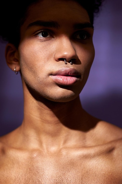 Closeup verticale portrait of fit young man with muscular neck on purple background hispanic model