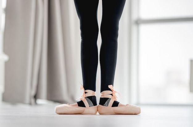 Photo closeup view of ballerina straightened legs staying in first position during dance class in choreography studio