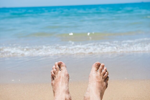 Closeup view of bare human feet on sand beach background. Summer vacation concept