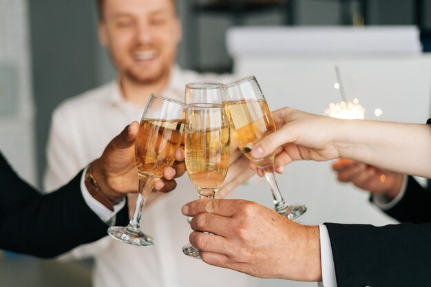 Closeup view of business team of multinational employees holding clinking glasses of champagne