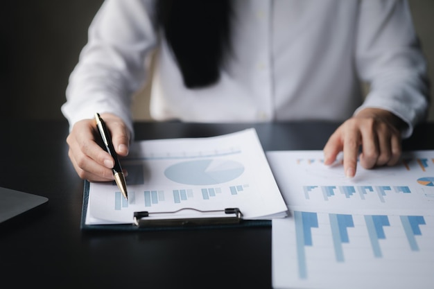 A closeup view of a businessman pointing at a bar chart on a company financial document prepared by the Finance Department for a meeting with business partners Financial concept