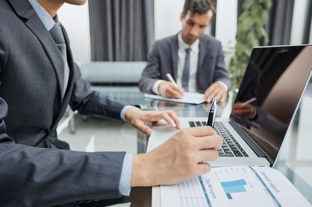 Closeup view of businessman working at sunny office on modern laptop