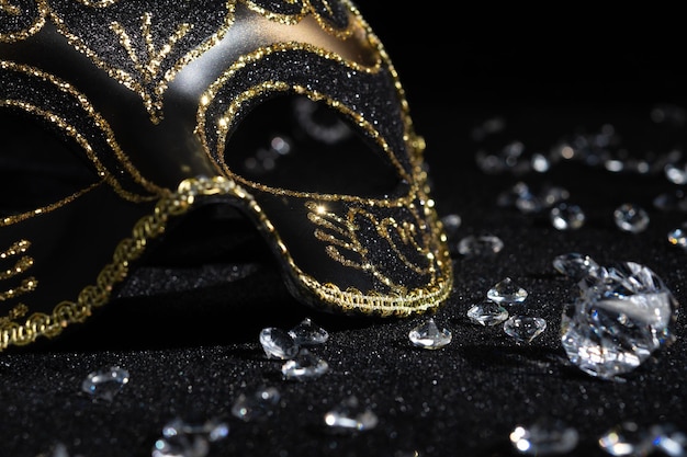 Близкий вид карнавальной золотой маски с бриллиантами на черном фоне
