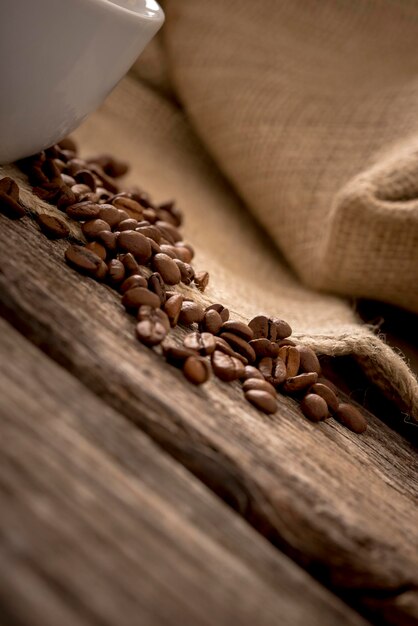 Closeup view of coffee beans scattered on rustic textured wooden desk