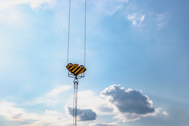 Closeup view of crane hook against blue sky.