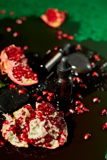 A closeup view of a dark glass dropper bottle of essential oil placed amidst vibrant pomegranate seeds and slices highlighting a natural and holistic wellness theme