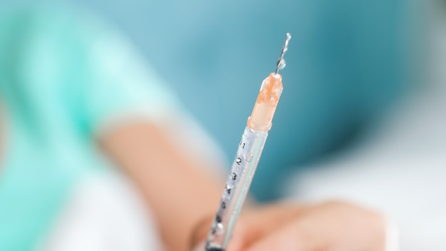 Closeup view of droplets of medicines on the syringe needle edge.